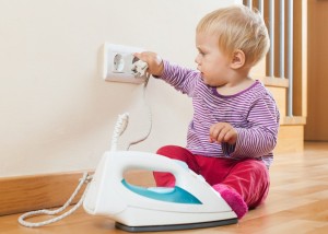 Toddler playing with electric iron at home